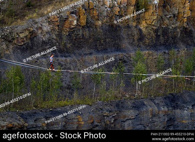 02 October 2021, Lower Saxony, Osnabrück: A man walks across a slackline. Germany's best slackliners want to conquer the Piesberg Quarry on a 350-meter course