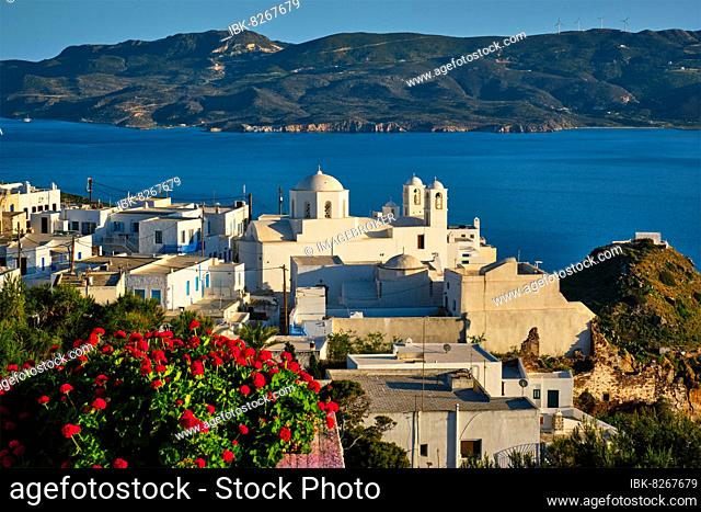 Picturesque scenic view of Greek town Plaka on Milos island over red geranium flowers and Orthodox greek church, Plaka village, Milos island, Greece, Europe