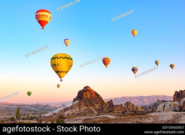 Flying hot air balloons and rock landscape at sunrise time in Goreme, Cappadocia, Turkey