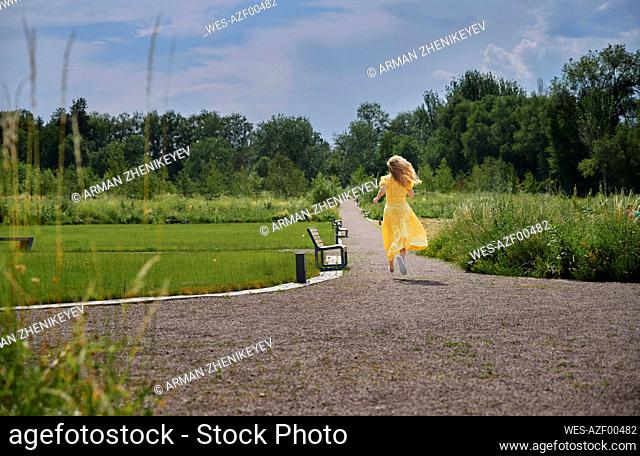 Carefree woman running on footpath in park