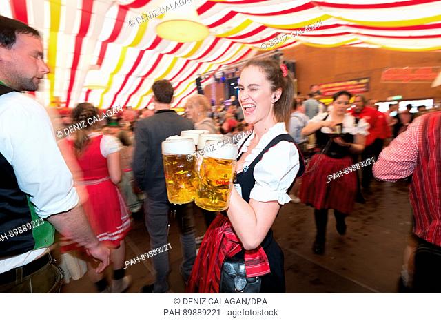 dpatop - A waitress carries beer inside a beer tent at the Stuttgart Spring Festival in Stuttgart, Germany, 15 April 2017