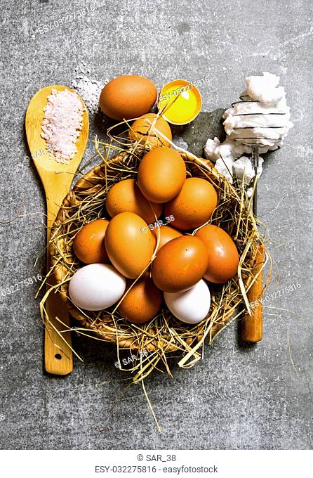 Set a basket of eggs, whisk with beaten egg . On a stone background. Top view