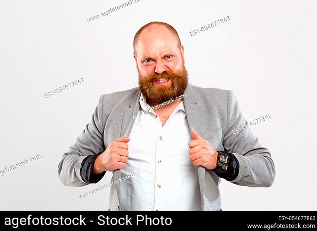 Dissatisfied man with beard in gray jacket on empty isolated background