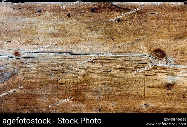 A horizontal rustic wooden board of aged wood. The wood is weathered, heavily textured and coloured yellow, gold and brown