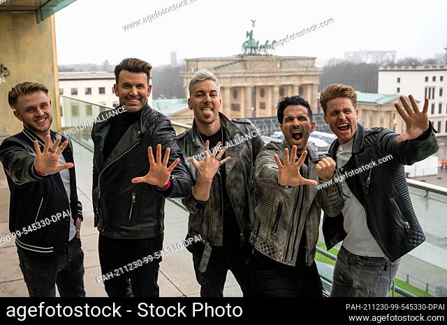 30 December 2021, Berlin: The band Team 5ünf stands on the terrace of the Akademie der Künste in front of the Brandenburg Gate during a photo session
