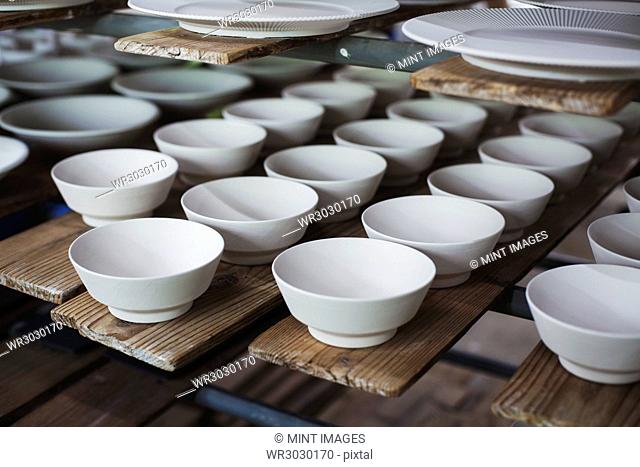 High angle close up of white bowls and plates in a Japanese porcelain workshop
