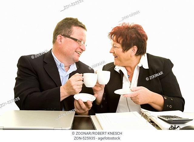 Zwei Arbeitskollegen trinken zusammen am Schreibtisch Kaffee