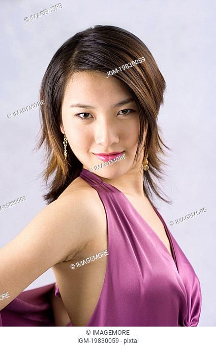 Young woman wearing a purple formal dress, smiling, head turned