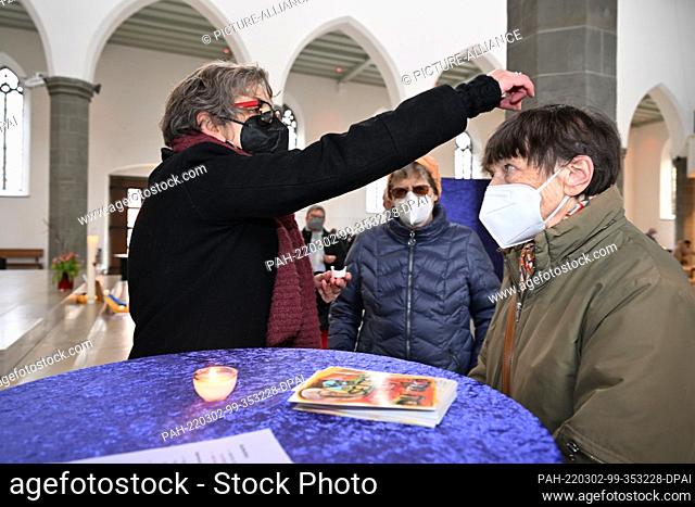 02 March 2022, Baden-Wuerttemberg, Ravensburg: Parish priest Christine Mauch makes a cross on the forehead of a senior citizen in the parish church of St