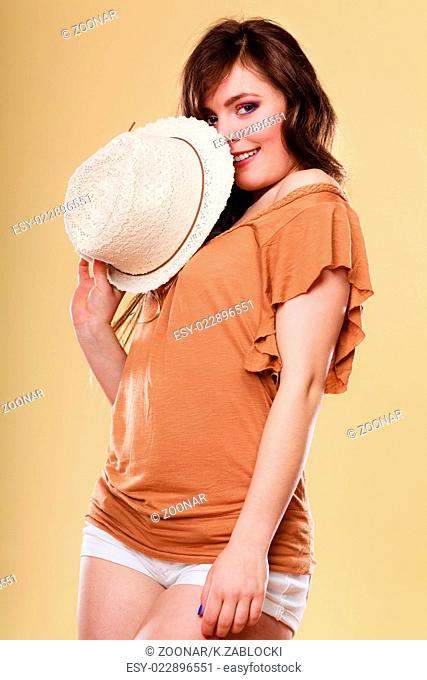 Cute girl holds summer straw hat covering her face