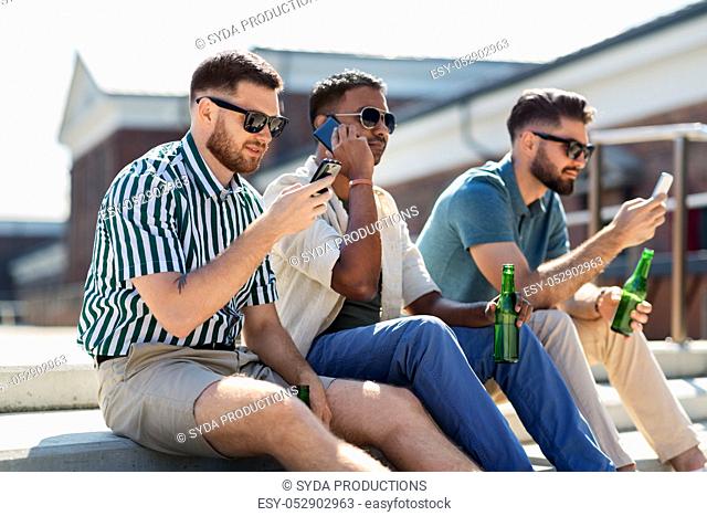 men with smartphones drinking beer on street