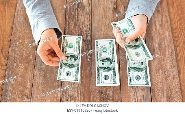 business, finance, saving, banking and people concept - close up of woman hands counting us dollar money on wooden table