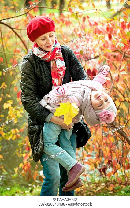 girl and mother are hiding behind a tree in the autumn park