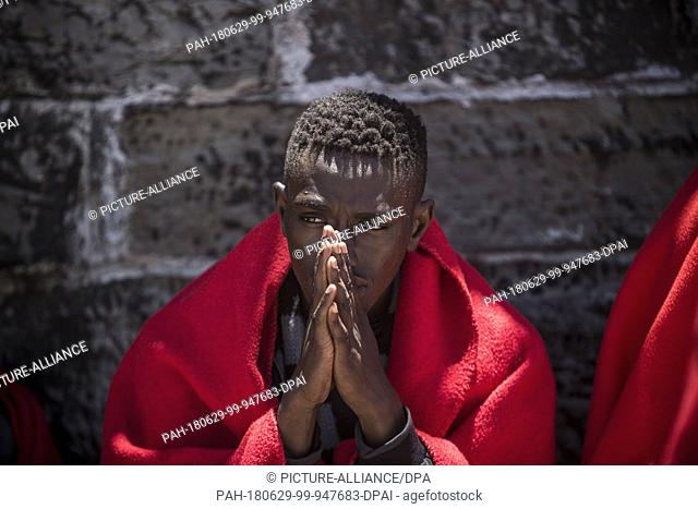 29 June 2018, Spain, Tarifa: An African migrant sits at the port of Tarifa covered in red blankets after being rescued from the Strait of Gibraltar