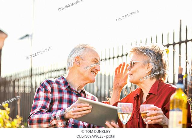 Senior couple on city rooftop garden using digital tablet