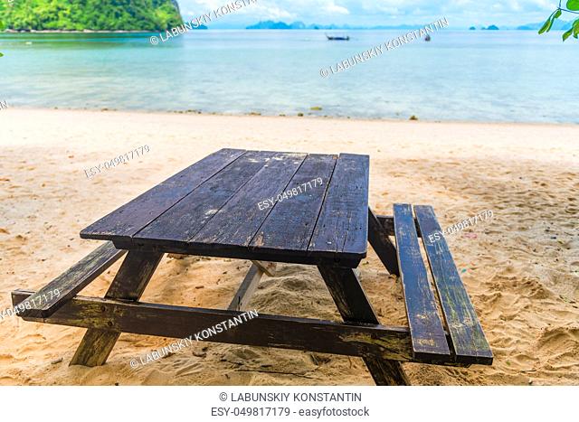 wooden table and benches on a sandy beach on the background of the sea