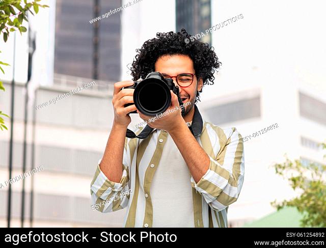 smiling man or photographer with digital camera