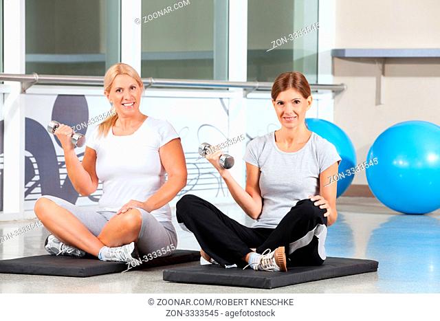 Zwei lächelnde Frauen beim Kraftsport im Fitnesscenter