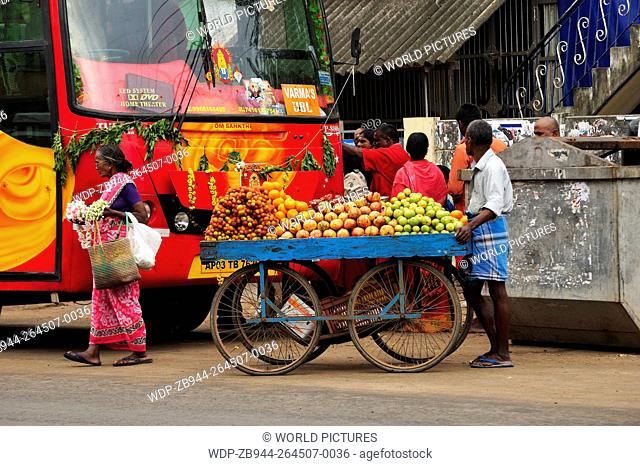 fruit vendor in front of colourful bus, Chidambaram, Tamil Nadu, India