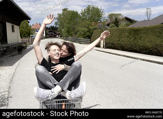 Mother and son fooling around with a shopping cart, in Gaissach, Bavaria, Germany