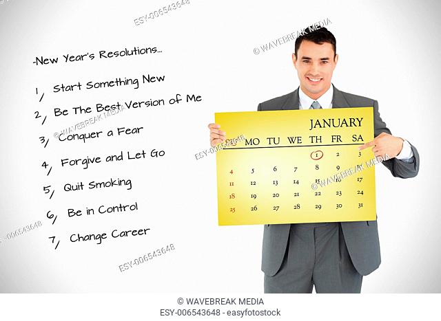 Composite image of businessman pointing at calendar he is holding