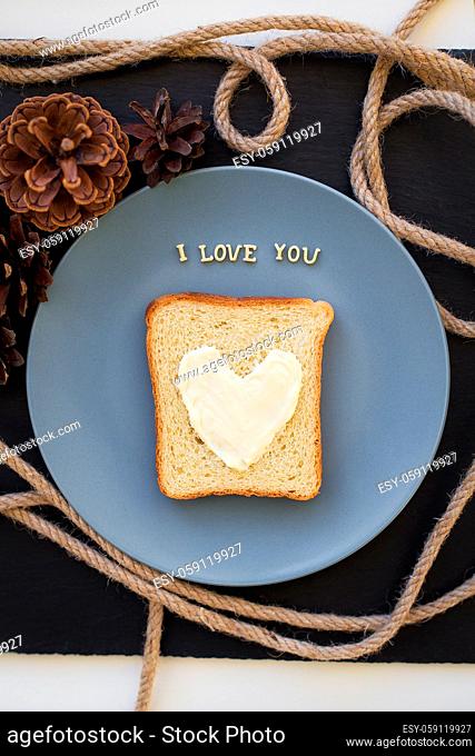 sandwich for breakfast in the form of heart with cheese on a blue plate and black background with cones inscription I love you