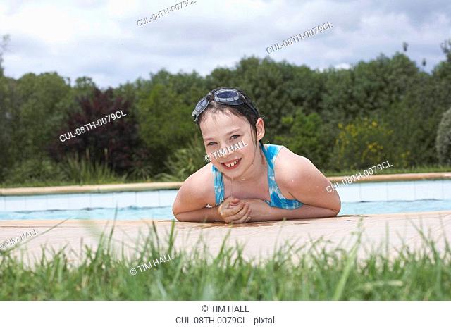 Young girl smiling by swimming pool