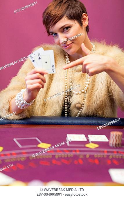 Woman in a casino sitting at table and showing cards