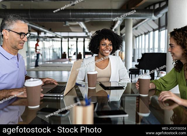 Happy business colleagues sitting together at desk