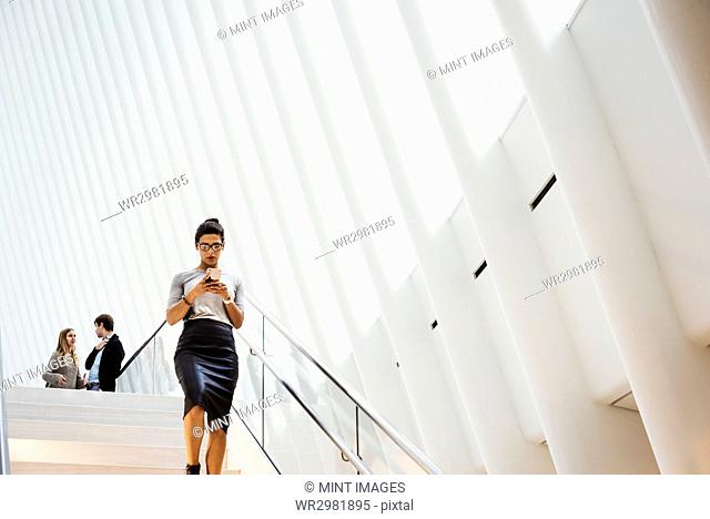 A woman walking down a staircase in the Oculus building, the World Trade Centre hub, modern architectural design with a ribbed vaulted roof space