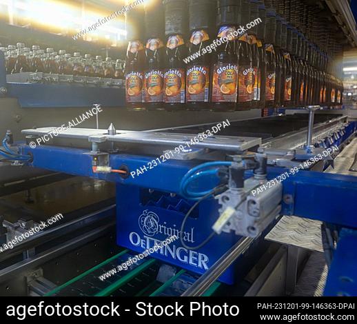 01 December 2023, Bavaria, Oettingen: A cola mix drink is filled into crates at the Oettinger brewery. Due to the difficult situation on the German beer market