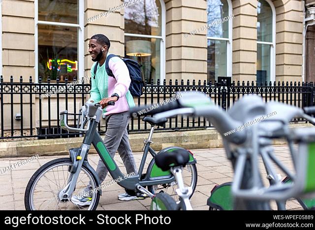 Happy man with electric bicycle walking on footpath