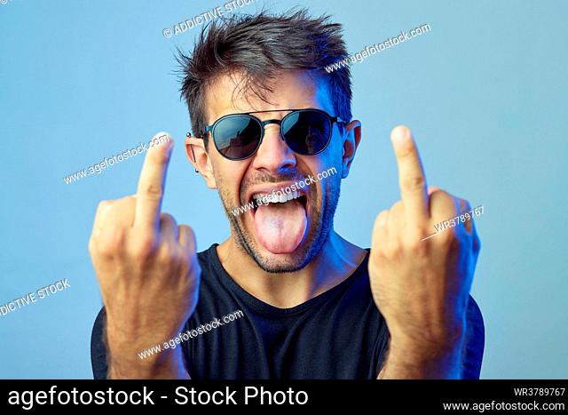 young man, sticking out tongue, middle finger, obscene gesture