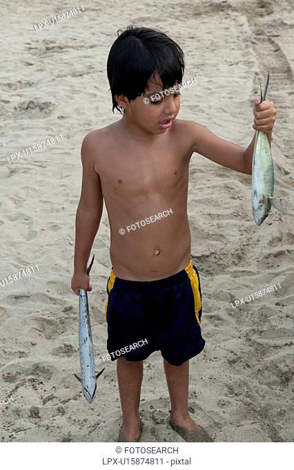 Boy holding fish in both hands, Sayulita, Nayarit, Mexico