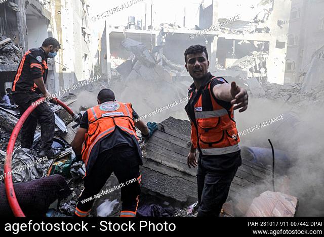 17 October 2023, Palestinian Territories, Rafah: A member of the Palestinian Civil Defense recovers bodies and injured people from under the rubble after an...