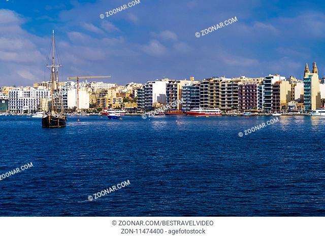 Panoramic day view with modern buildings by the waterfront promenade, viewed from Valletta