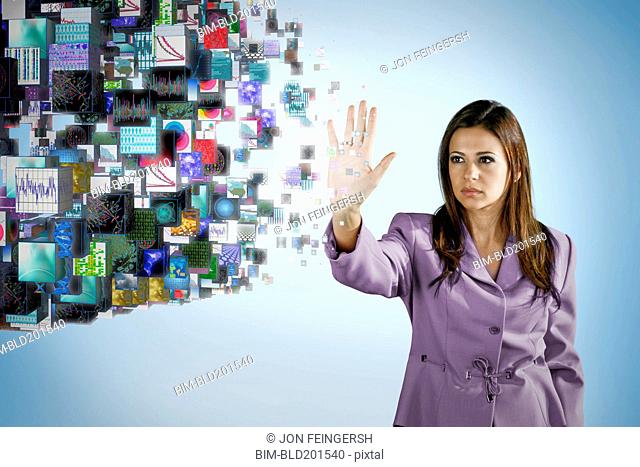 Businesswoman holding hand out toward digital images