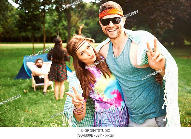 Portrait of young boho couple making peace signs at festival