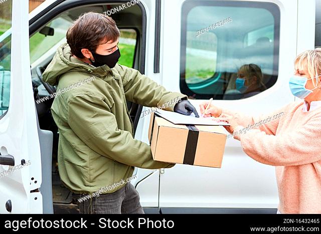 Kundin mit Mundschutz gibt Lieferdienst Paketbote Unterschrift bei Übergabe vor Transporter