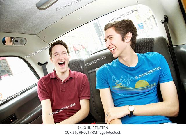 Men laughing in backseat of car