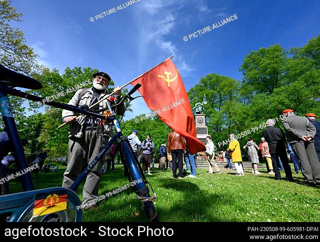 08 May 2023, Saxony, Dresden: Hans-Jürgen Westphal, political activist, stands with a flag of the former Soviet Union, at a commemoration ceremony for...