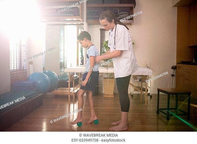 Side view of boy standing on stress balls with female therapist