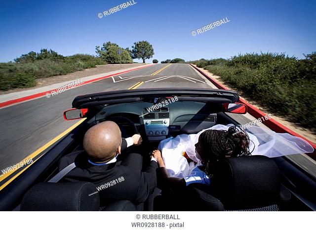 Rear view of a newlywed couple in a car
