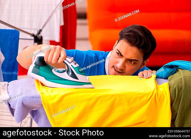 Young man doing ironing at home