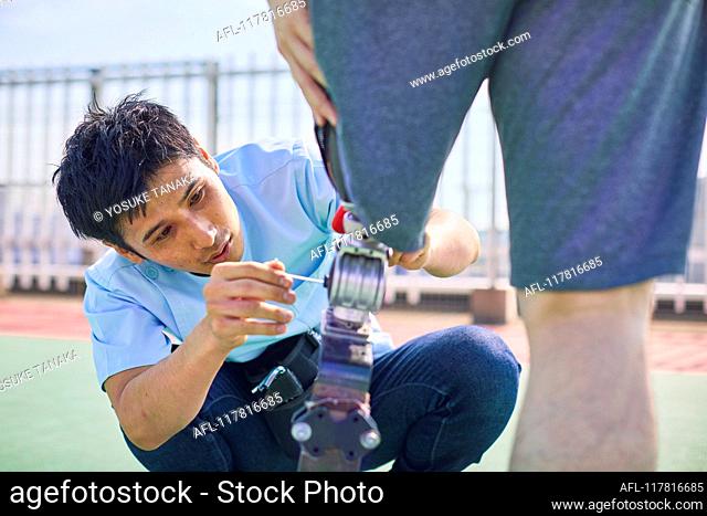 Japanese prosthetist working with amputee on rooftop