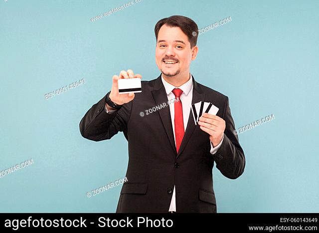Happiness business man holding many cards. One bank card will replace all your cards. Indoor, studio shot, isolated on light blue or gray background