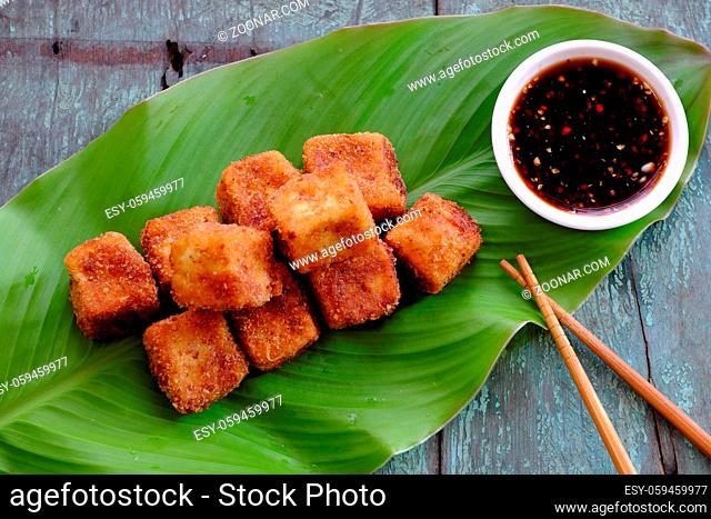 Frugal vegetarian food from Vietnamese cuisine, fried tofu with spice power, cover with crispy flour, homemade food on green leaf background