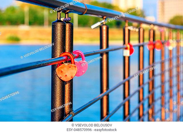 Colorful metal locks hanging on black railings in the sunrise light