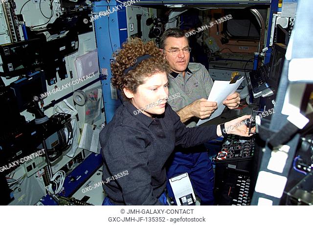 Astronauts Susan J. Helms and James S. Voss, Expedition Two flight engineers, work together to check out some data in the Destiny laboratory aboard the...