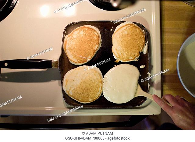 Pancakes on Skillet, One being Flipped